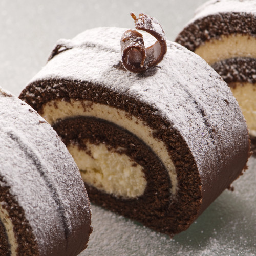 Slices of swiss roll chocolate cake on frosted glass plate